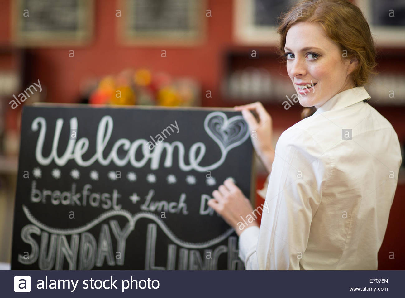 portrait-of-waitress-chalking-menu-on-blackboard-in-restaurant-e7076n